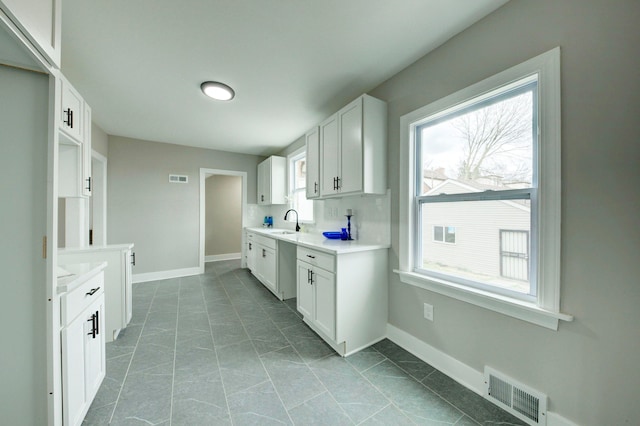 kitchen with white cabinets, sink, plenty of natural light, and dark tile floors