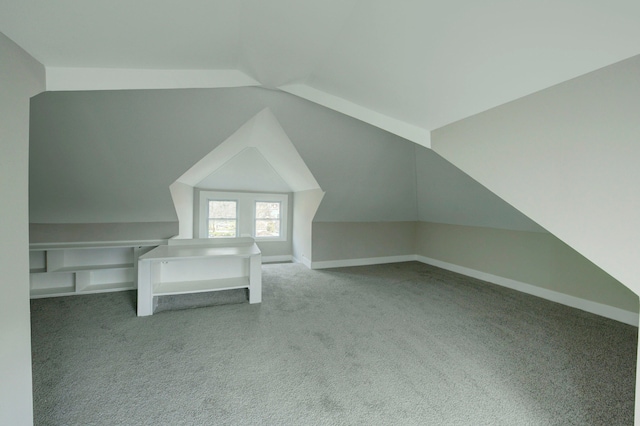 additional living space featuring lofted ceiling and dark colored carpet