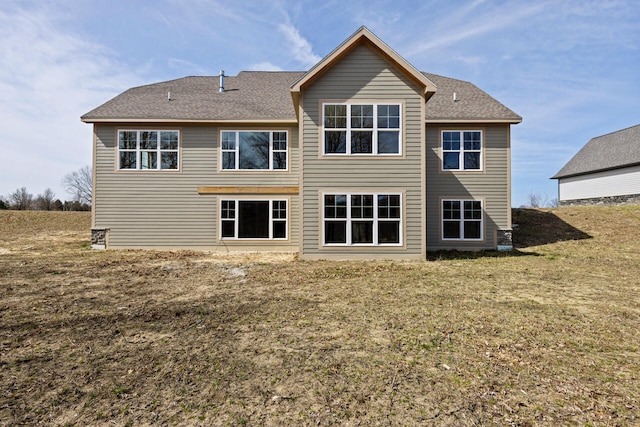 back of house with a yard and a shingled roof