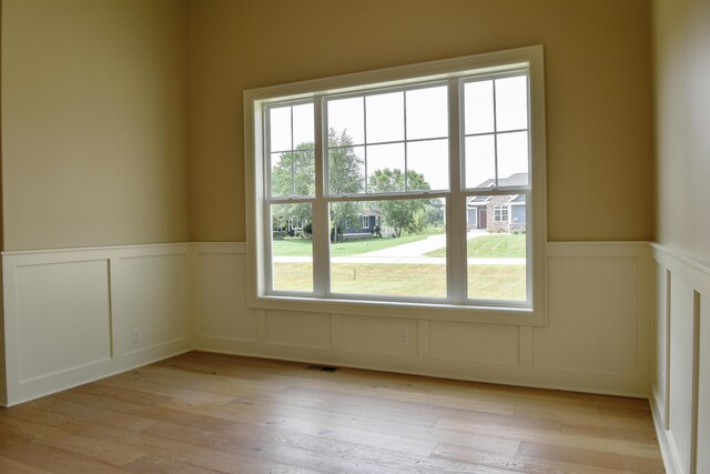 spare room featuring a wainscoted wall, visible vents, and light wood-type flooring