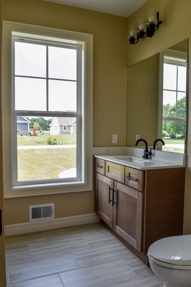 bathroom with a wealth of natural light, visible vents, toilet, and vanity