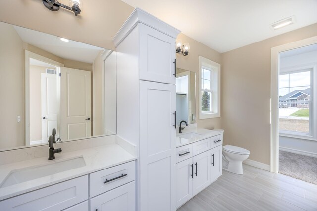 bathroom with a sink, two vanities, and a healthy amount of sunlight