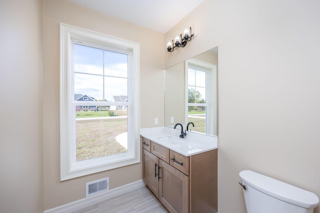 bathroom featuring vanity, toilet, a healthy amount of sunlight, and visible vents