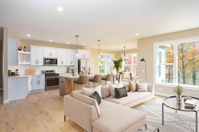 living area with recessed lighting, light wood-style floors, and baseboards