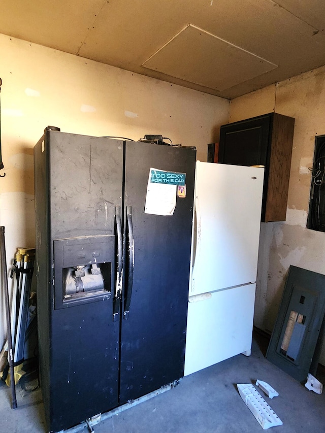 interior space featuring concrete floors, white refrigerator, and black fridge