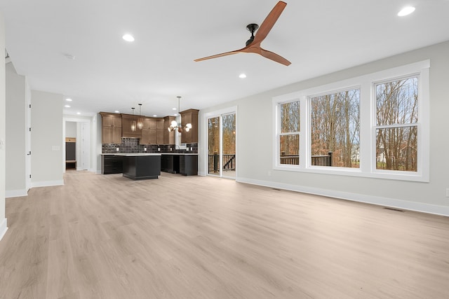 unfurnished living room with light hardwood / wood-style flooring and ceiling fan with notable chandelier