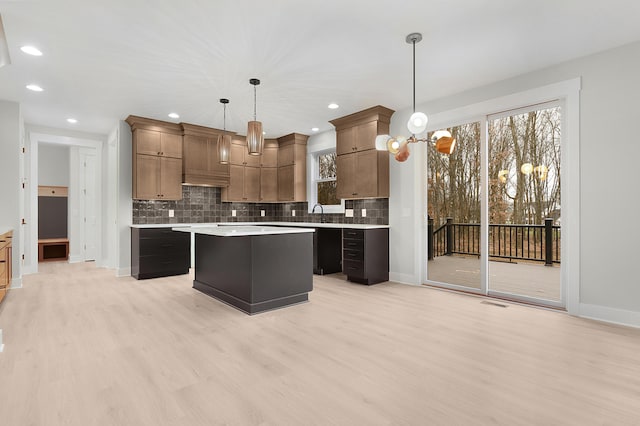 kitchen featuring decorative backsplash, a center island, decorative light fixtures, and light hardwood / wood-style flooring