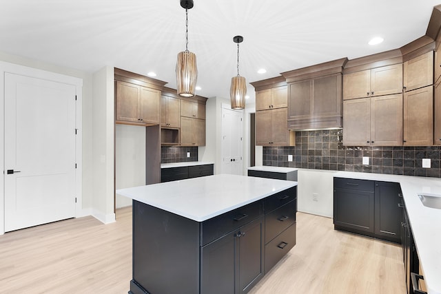 kitchen featuring pendant lighting, backsplash, light hardwood / wood-style flooring, a kitchen island, and custom range hood