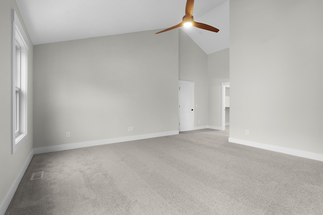 carpeted spare room with ceiling fan and high vaulted ceiling