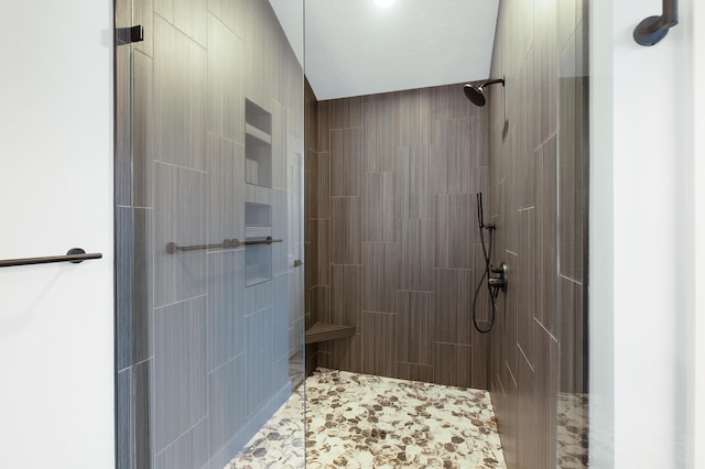 bathroom featuring a tile shower and a textured ceiling