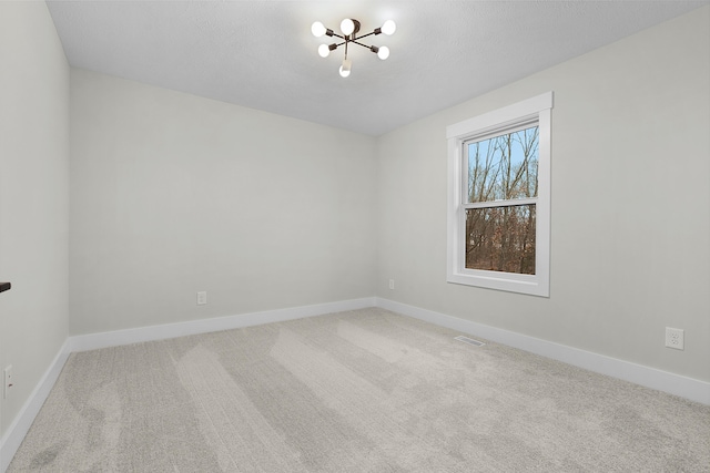 carpeted empty room featuring a notable chandelier