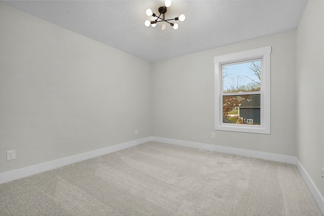 carpeted spare room with a chandelier