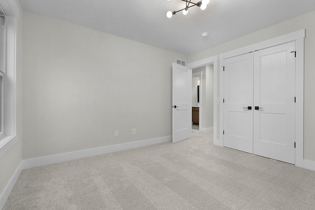 unfurnished bedroom featuring an inviting chandelier, light carpet, and a closet