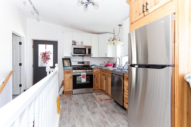 kitchen featuring decorative light fixtures, appliances with stainless steel finishes, light hardwood / wood-style floors, rail lighting, and a chandelier