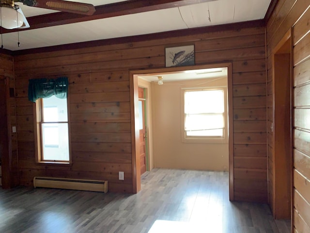 unfurnished room featuring dark hardwood / wood-style flooring, wood walls, ceiling fan, and a baseboard heating unit