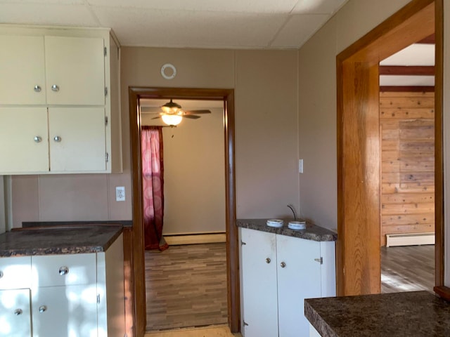 kitchen featuring light hardwood / wood-style flooring, a baseboard radiator, ceiling fan, and white cabinetry