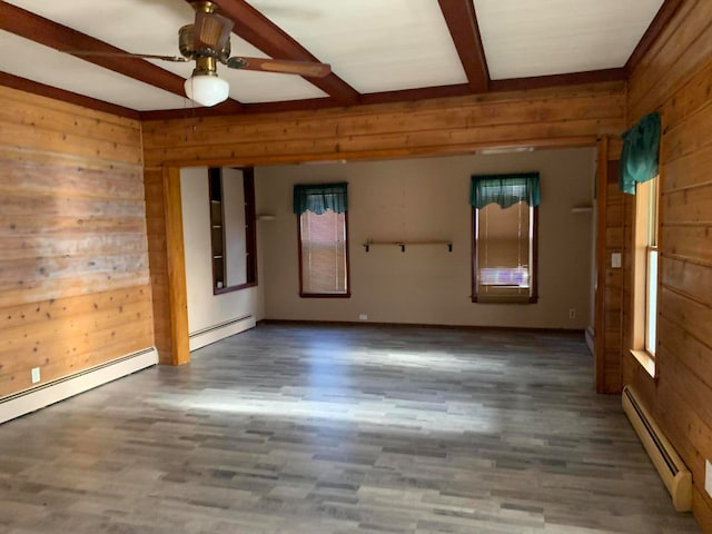 unfurnished room with beamed ceiling, wood walls, hardwood / wood-style flooring, and baseboard heating