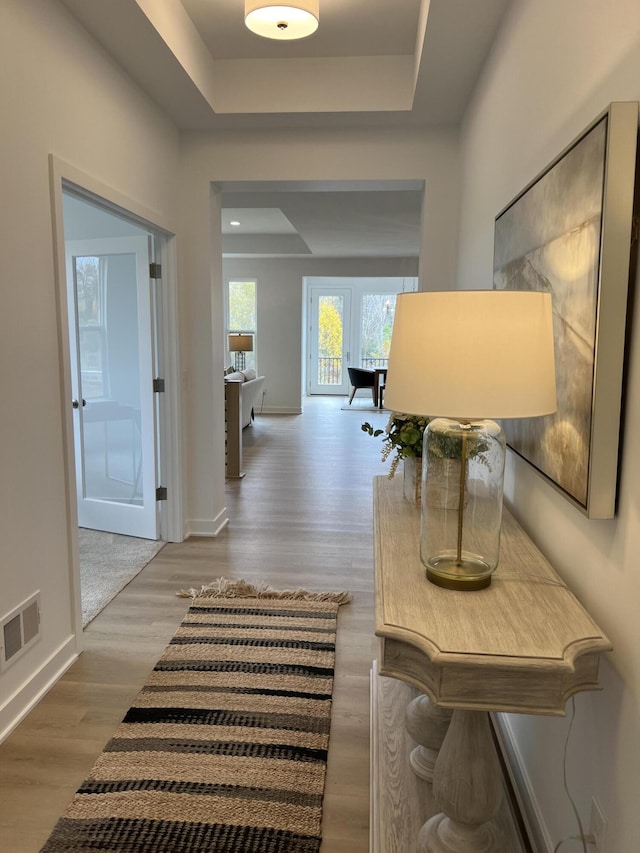 corridor featuring a tray ceiling and hardwood / wood-style floors