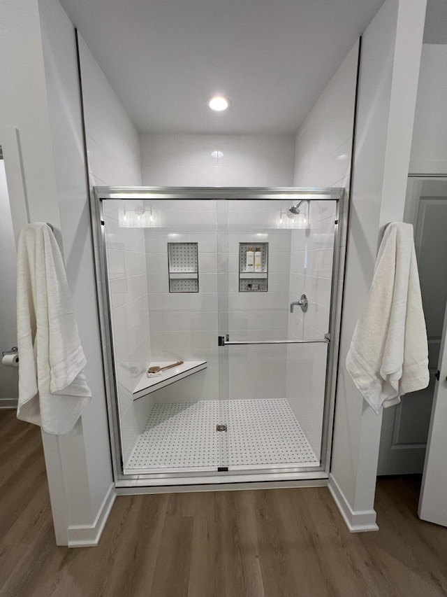 bathroom with wood-type flooring and a shower with shower door