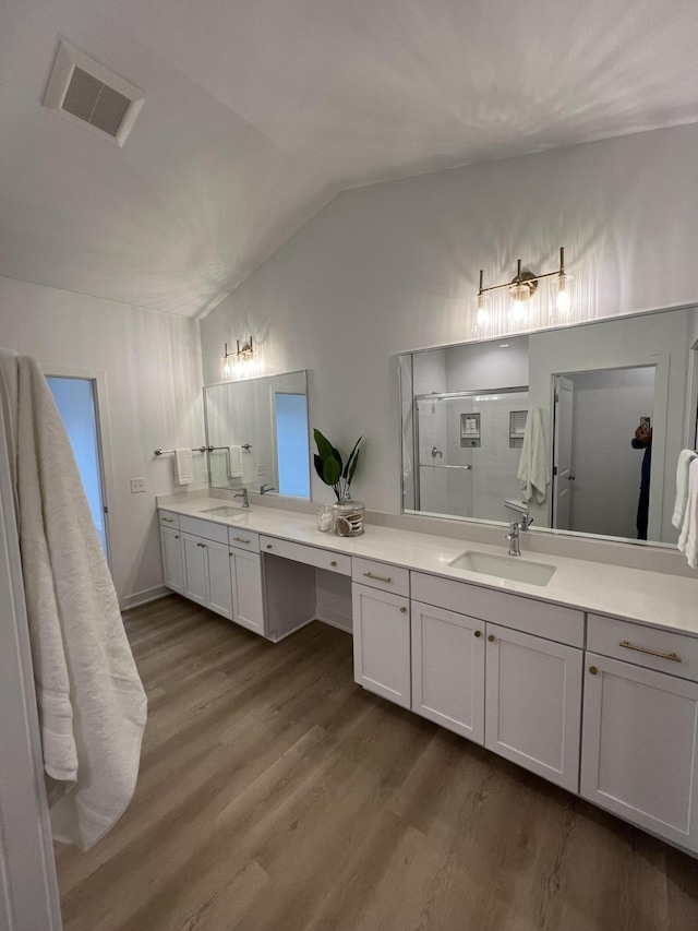 bathroom with hardwood / wood-style floors, vanity, lofted ceiling, and walk in shower