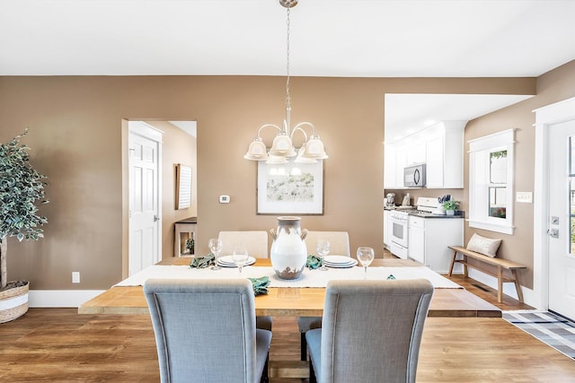 dining space featuring light wood-type flooring and an inviting chandelier