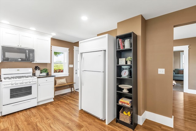 kitchen with white cabinets, light hardwood / wood-style floors, and white appliances