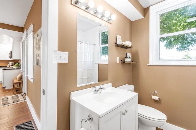 bathroom with hardwood / wood-style floors, vanity, toilet, and curtained shower