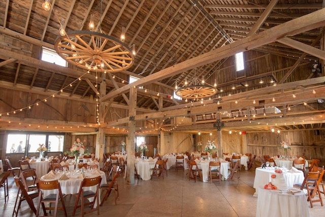 unfurnished dining area featuring high vaulted ceiling, a notable chandelier, and wood walls