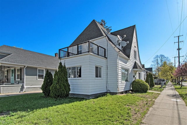 view of home's exterior with a yard and a balcony