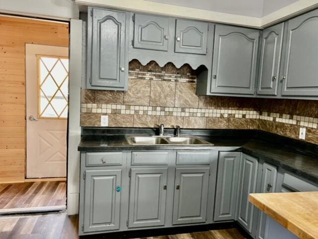 kitchen with dark hardwood / wood-style floors, sink, wooden walls, and tasteful backsplash