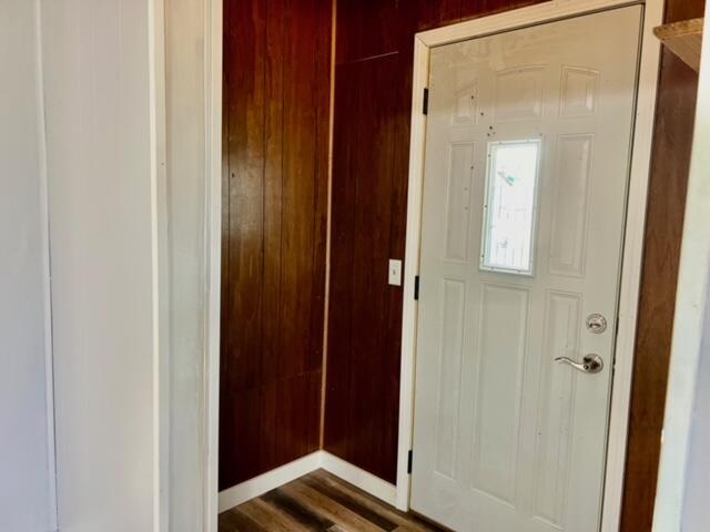 entryway featuring dark hardwood / wood-style flooring and wooden walls