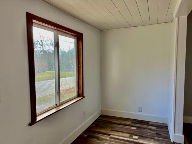 empty room with wood ceiling and dark wood-type flooring