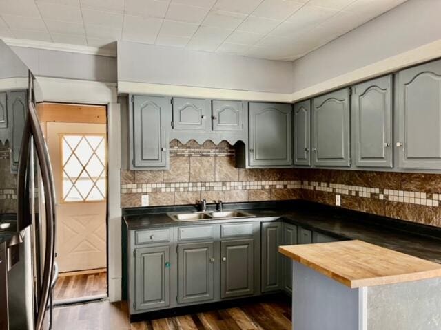 kitchen with backsplash, sink, dark hardwood / wood-style floors, stainless steel fridge, and butcher block counters