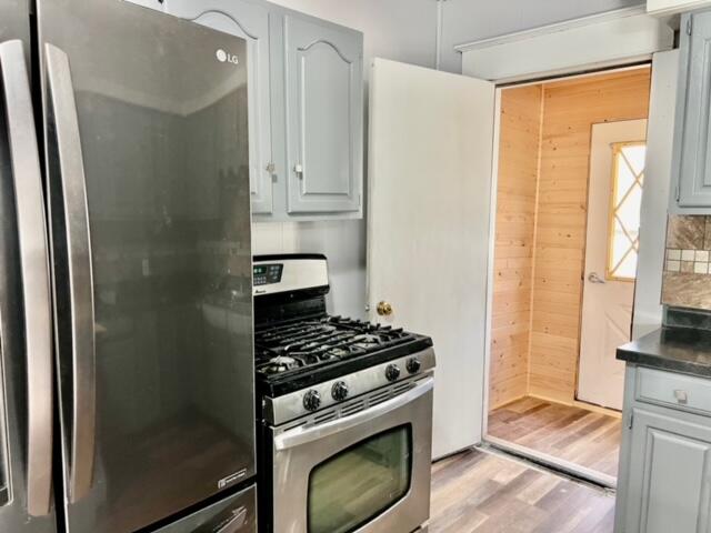 kitchen with decorative backsplash, appliances with stainless steel finishes, light wood-type flooring, and gray cabinetry