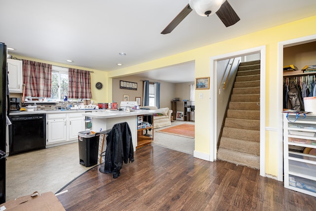 kitchen featuring ceiling fan, black dishwasher, wood-type flooring, white cabinetry, and a kitchen breakfast bar