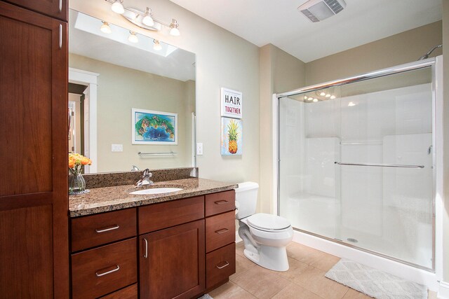 bathroom with a shower with door, tile flooring, toilet, and large vanity