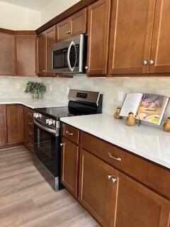 412 Coventry Rd, Battle Creek, MI 49015 - kitchen with backsplash, light wood-style floors, light countertops, and appliances with stainless steel finishes