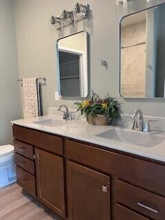 412 Coventry Rd, Battle Creek, MI 49015 - bathroom featuring double vanity, wood finished floors, toilet, and a sink