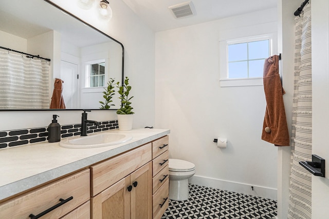 bathroom with vanity, toilet, and tasteful backsplash