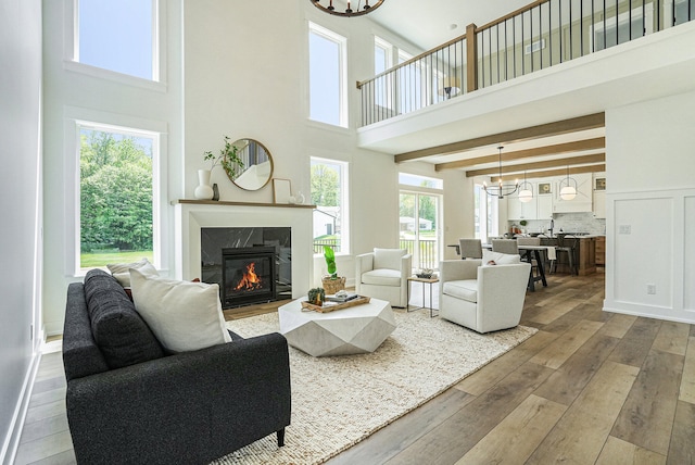 living room with wood-type flooring, a fireplace, a towering ceiling, and a notable chandelier