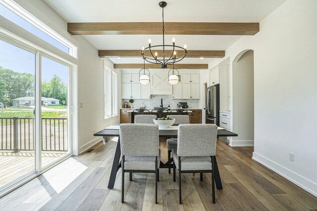 dining space with a chandelier, sink, beamed ceiling, and hardwood / wood-style flooring