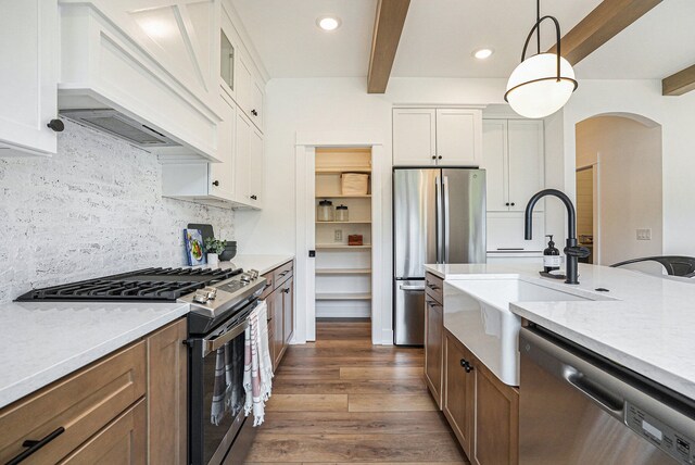 kitchen featuring pendant lighting, white cabinets, appliances with stainless steel finishes, and dark hardwood / wood-style flooring