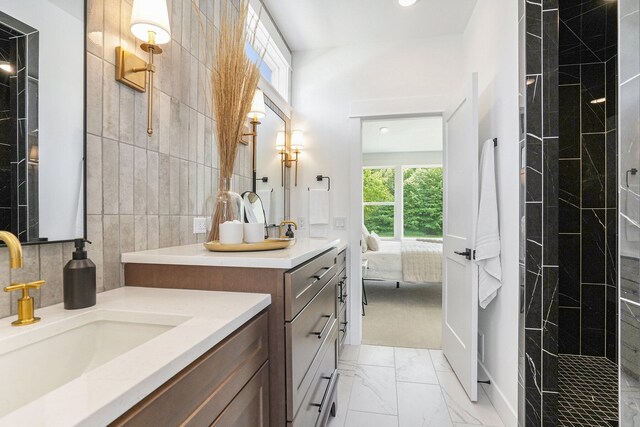 bathroom with a tile shower, tile walls, and vanity