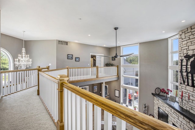 hall featuring light colored carpet and an inviting chandelier