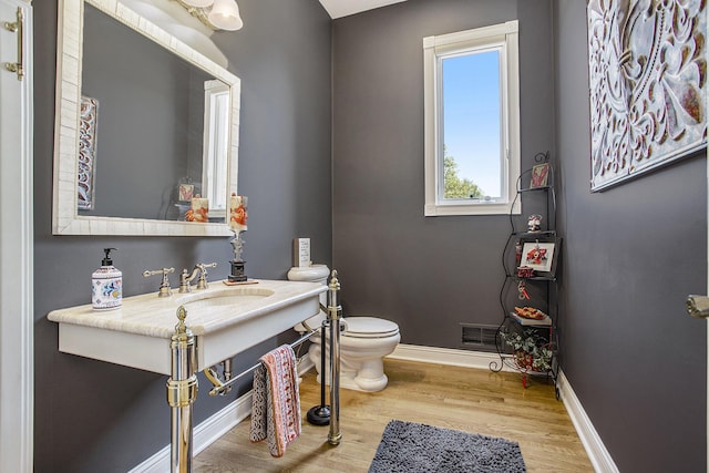 bathroom featuring wood-type flooring, toilet, and sink