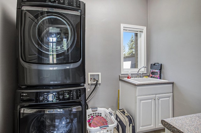 washroom with cabinets, stacked washer / drying machine, and sink