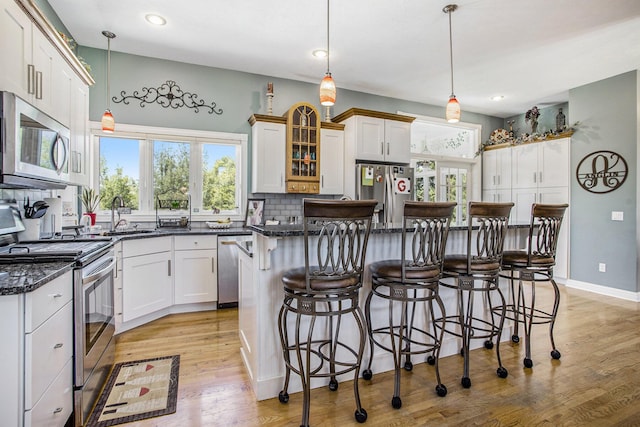 kitchen featuring white cabinetry, appliances with stainless steel finishes, a center island, and decorative light fixtures