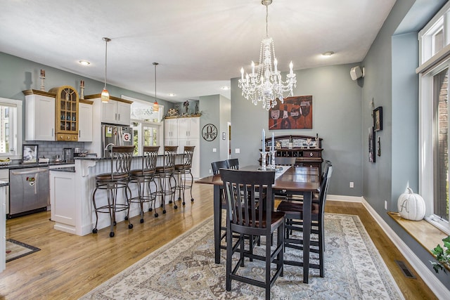 dining area with an inviting chandelier and light hardwood / wood-style flooring