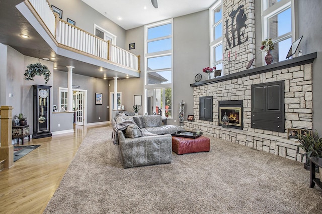 living room featuring a fireplace, light hardwood / wood-style floors, decorative columns, and a high ceiling