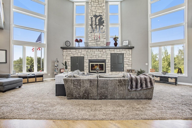 living room featuring wood-type flooring, a fireplace, and a high ceiling